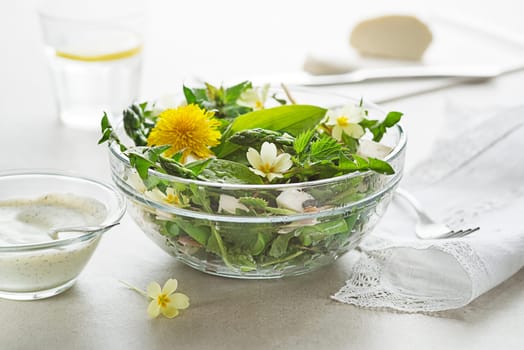 Spring salad with dandelion, asparagus, wild garlic, flowers, nettle and cream cheese. Healthy spring detox food ingredients.