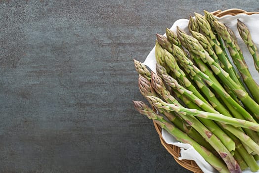 Asparagus. Fresh Asparagus. Pickled Green Asparagus in basket. Bunches of green asparagus on grey table closeup, top view- Image