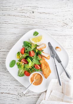 Crispy chicken steaks with green salad and tomato. Fried chicken meal with vegetables