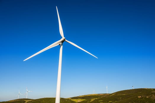 Wind turbines on a beautiful blue sky in a mountain wind farm in Sardinia. Renewable energy concept, green energy generation. Energy industry.