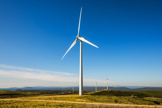 Wind turbines on a beautiful blue sky in a mountain wind farm in Sardinia. Renewable energy concept, green energy generation. Energy industry.