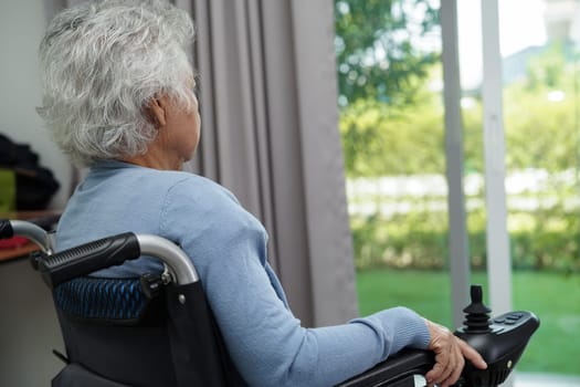 Asian elderly woman disability patient sitting on electric wheelchair in park, medical concept.