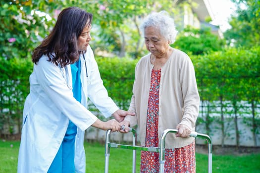 Doctor help Asian elderly woman disability patient walk with walker in nursing hospital, medical concept.