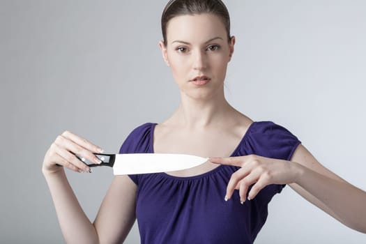 A young woman is playing with a sharp kitchen knife