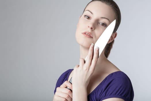 A young woman is playing with a sharp kitchen knife