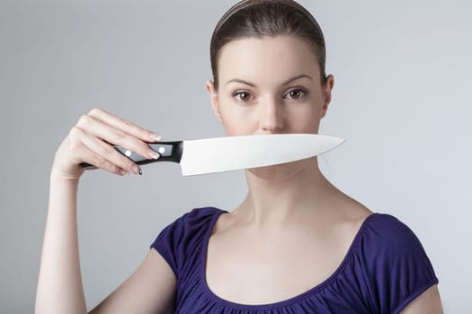 A young woman is playing with a sharp kitchen knife
