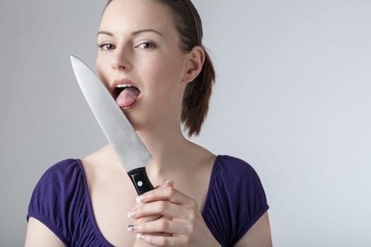 A young woman is playing with a sharp kitchen knife