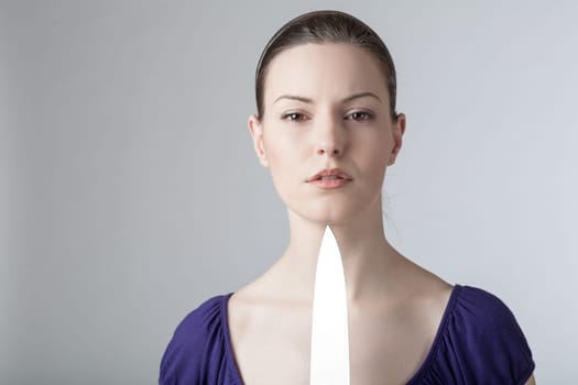 A young woman is playing with a sharp kitchen knife