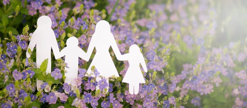 Family paper cut out is standing in a meadow, parents with daughter and son, environment concept, spring and summer season