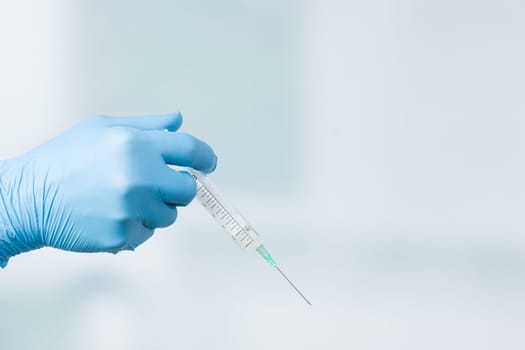Close up of doctor's hand in medical gloves with a syringe ready for injection