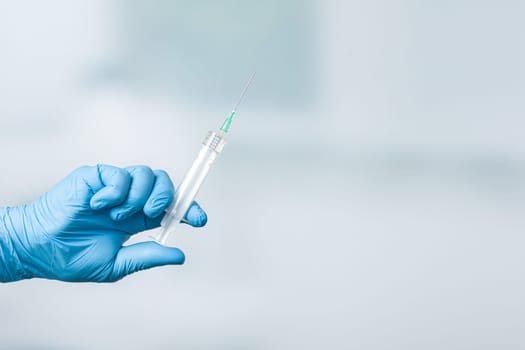 Close up of doctor's hand in medical gloves with a syringe ready for injection