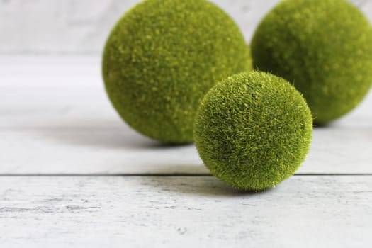 Green grass balls on a light wooden background..