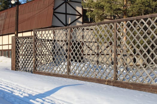 Beautiful bright house with a reddish-brown roof and a patterned carved fence. Winter. High quality photo