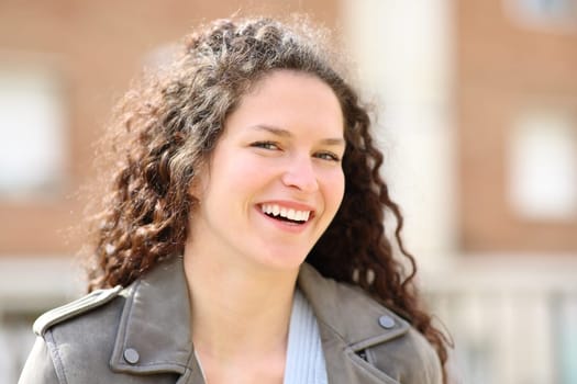 Happy woman smiling at camera standing in the street