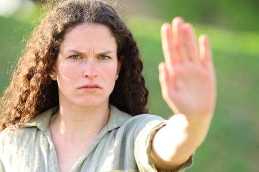 Angry woman gesturing stop with palm in a park
