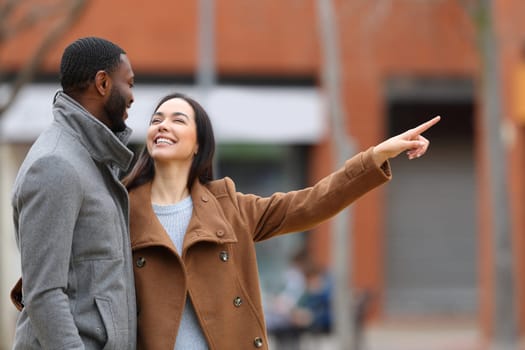 Interracial couple talking and pointing in the street