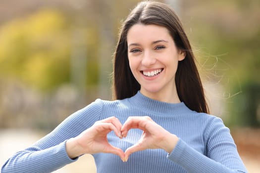 Happy teen doing heart shape in a park