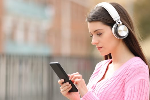 Serious teen listening to music browsing on phone