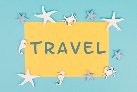 The word travel is standing on a yellow colored paper, sea stars, seahorses and crab bulding a frame, summer vacation, tourism destination