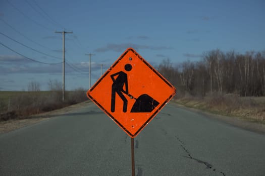 road construction rural street orange traffic sign man at work clouds country sky