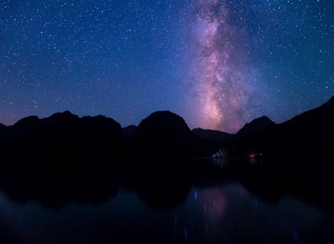 Night sky with prominent view of Milky Way over the lake Iskanderkul in the mountains of Tajikistan
