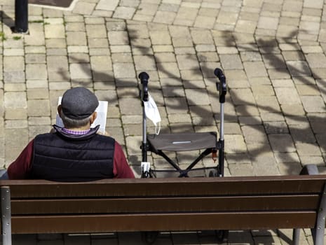 Detail of elderly person resting and reading after a walk
