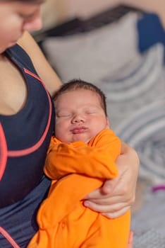 Young mother holding her sleeping newborn baby in her arms