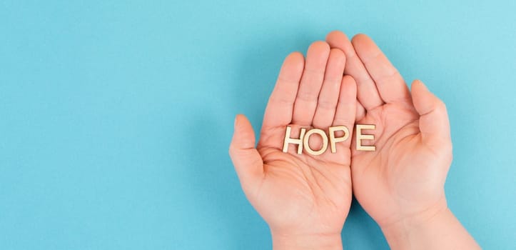 Holding the word hope in the palm of the hands, trust and believe concept, having faith in the future, hopeful positive mindset