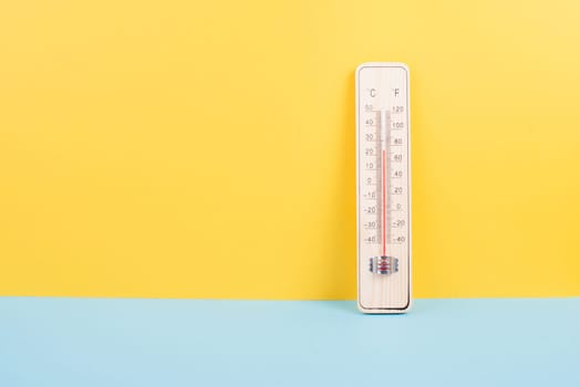 Thermometer on a yellow and blue colored background, measure the temperature, weather forecast, global warming and environment discussion, summer season