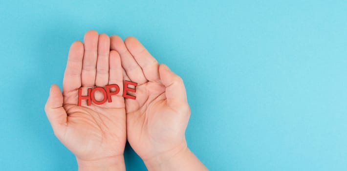 Holding the word hope in the palm of the hands, trust and believe concept, having faith in the future, hopeful positive mindset