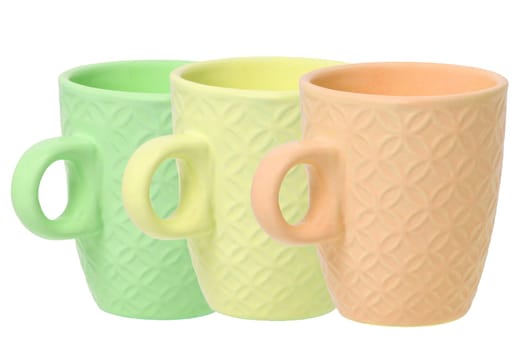 Mug of coffee. Closeup of three empty green, yellow and orange ceramic cups with space for label isolated on a white background. Concept morning coffee. Space. Macro.