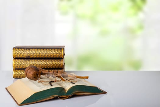 Closeup of a antique book with a tobacco pipe on them and a pair of glasses and a stack of three books in front of bright background. The teachers day. Back to school. Space.