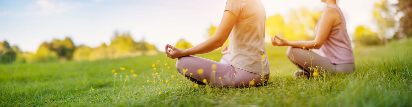 Two women sitting in active wear in lotus position in nature. Concept of healthy lifestyle.