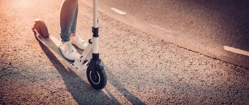 Woman riding on scooter on asphalt road in summer. Concept of city life.