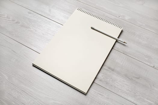 Photo of blank notepad and pencil on light wooden background. Blank objects for placing your design.