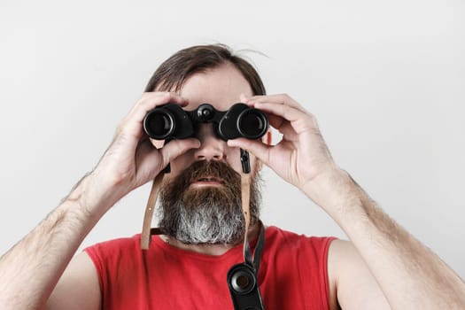 Man with binoculars. Bearded man looking through binocular.