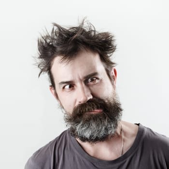 Man with stupid mug. Happy freak bearded shaggy man grimacing and showing tongue.