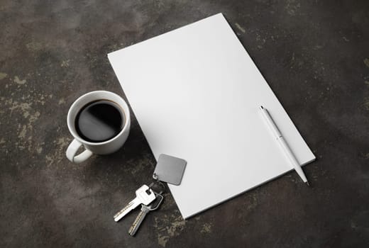Blank letterhead, key, pen and coffee cup on concrete background. Template for branding identity.
