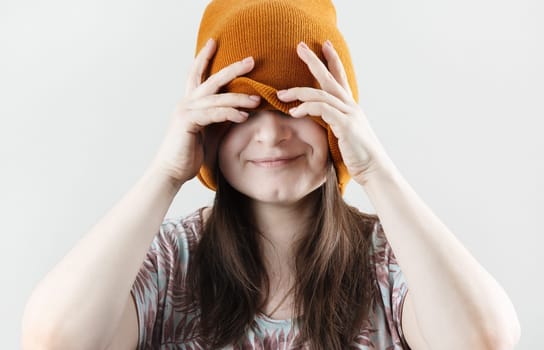 Smiling woman covering eyes through knitted hat. Woman hiding face.