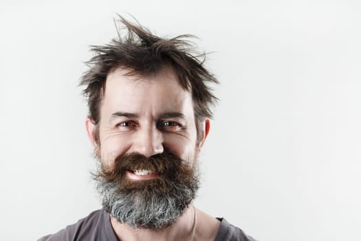 Happy smiling bearded shaggy man. Studio portrait of an unshaven man.