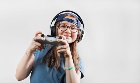 Teen girl in headphones plays video games with a gamepad in her hands. Gamer girl.
