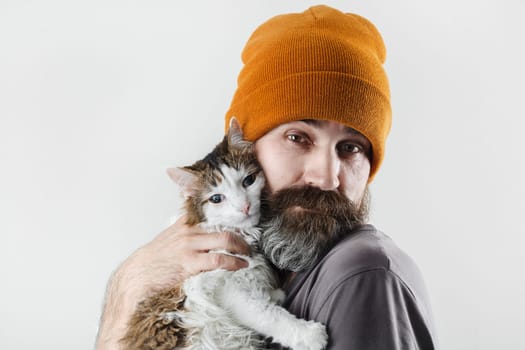 Bearded man hugging a cat. Hipster man in a hat and his beloved cat.