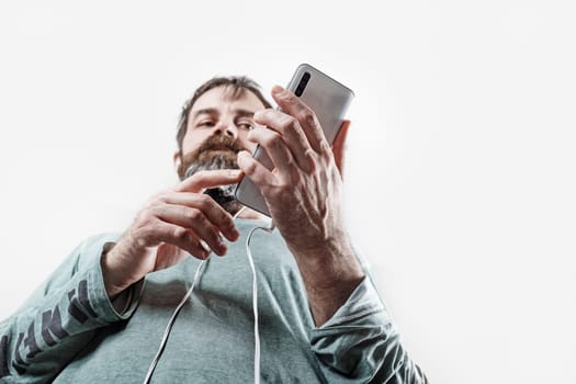Bearded man with a smartphone in his hands. Serious man uses smartphone. Selective focus.