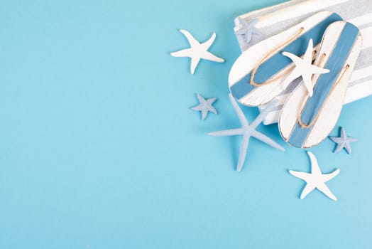 Blue colored summer and vacation background, slippers and sea stars building a frame, copy space for text, holiday and tourism concept