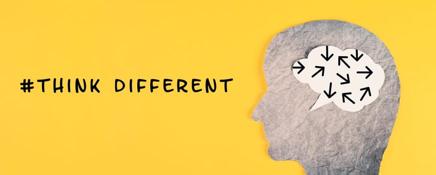 Think different stands on the yellow background, head with brain, being a nonconformist, standing out from the crowd, creative and visionary concept