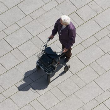 an old woman with a walker walking through the city