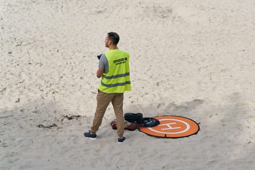 User of a drone on the beach of Kolobrzeg on the Baltic Sea in Poland. Translation: UAV operator, keep distance