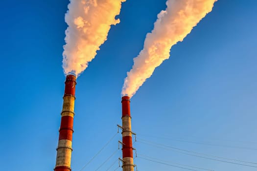 white smoke is coming out of the pipes in the blue sky. High quality photo