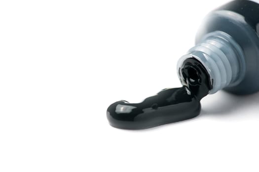 Close-up of an open tube of black acrylic artist paint oozing out on a white background.