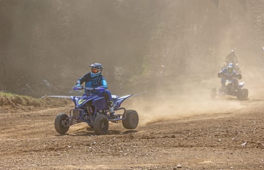 MOHELNICE,  CZECH REPUBLIC - APRIL 16, 2022: Three riders on a quad bike in the dust in International Championship of Czech Republic in Sidecarcross, category Quad on April 16, 2022 in Mohelnice.